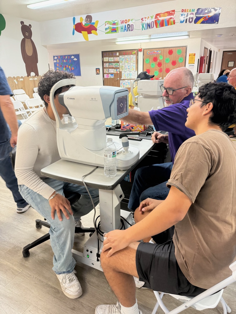 Isaac learning to use an autorefractor at a Lions Club vision screening